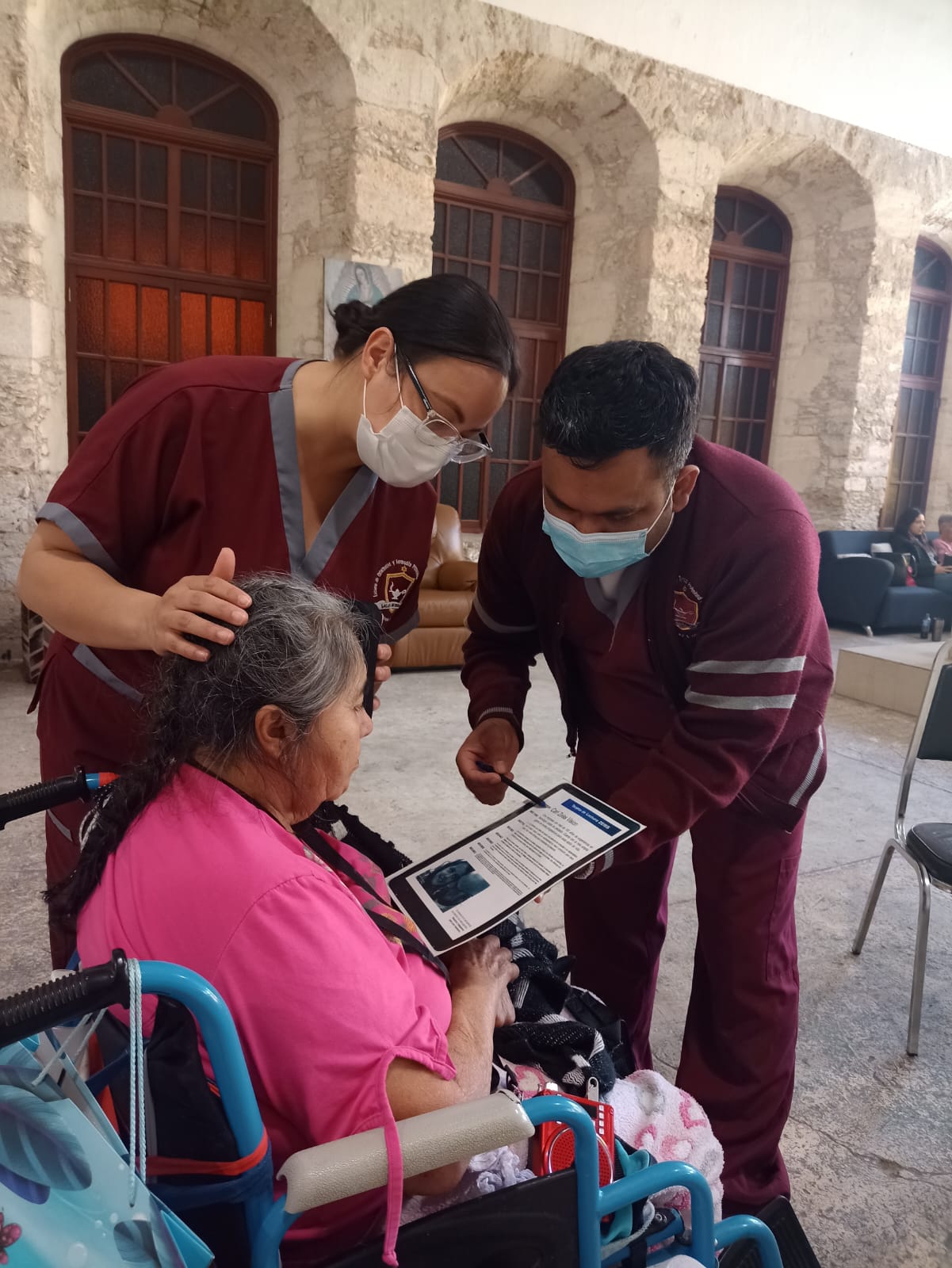 Estudiante brindando atención y compañía a una persona adulta mayor en silla de ruedas durante una brigada comunitaria.